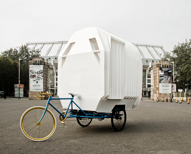 Una casa movil sobre un triciclo hecha con planchas de plástico 